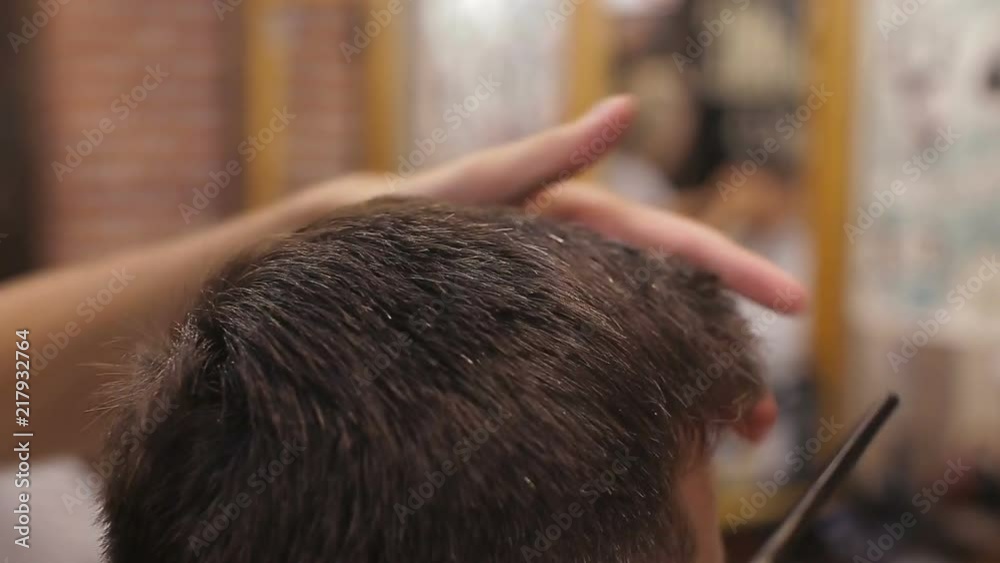 Master cuts hair and beard of men in the barbershop, hairdresser makes hairstyle for a young man Master cuts hair and beard of men in the barbershop, hairdresser makes hairstyle for a young man