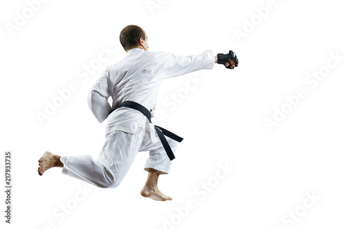Adult athlete trains a punch with his hand in a jump against a white background isolated