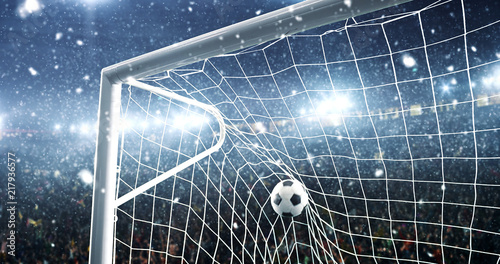Photo of the ball that flies into a goal on a professional soccer stadium while it s snowing