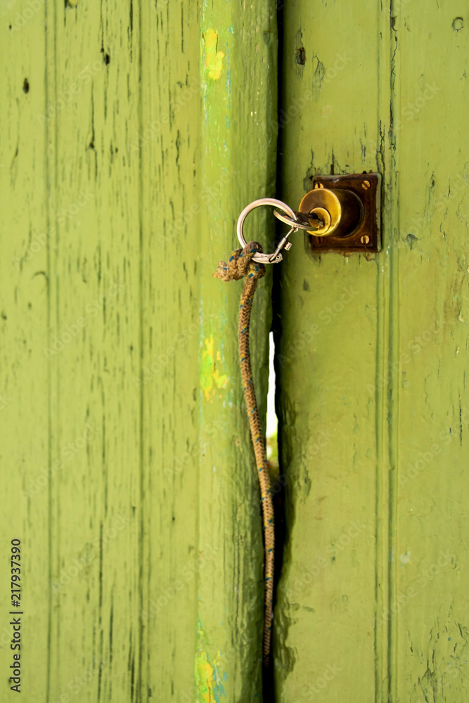 Key with a band on a green door - a minimalism composition Key with a band on a green door - a minimalism composition