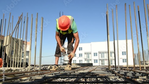 Reinforcing of concrete. Worker knitting steel rods