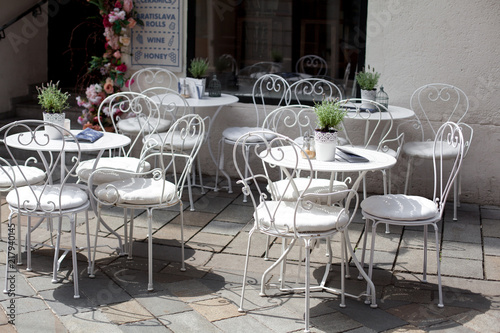 outdoor terrace of cafe with beautiful white wrought iron chairs and table in sunny summer day. photo