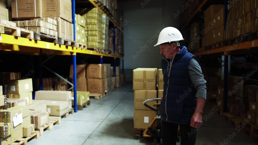 Senior male warehouse worker pulling a pallet truck. Senior male warehouse worker pulling a pallet truck.