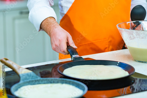 kitchen Preparation: the chef fries fresh pancakes in two pans