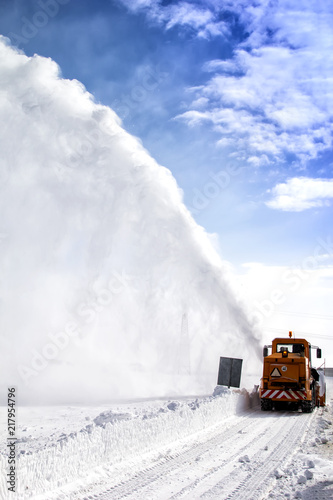 Snow-covered road cleaning by snow removal machine. Snow truck in highway.