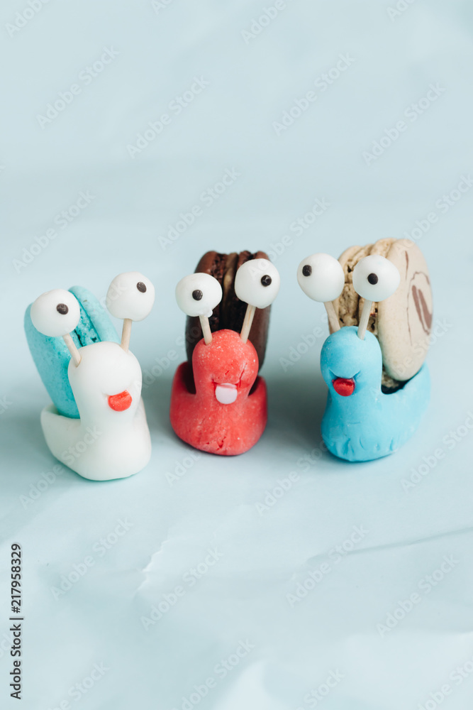 Creative snail decorations with delicious macaroons on blue table