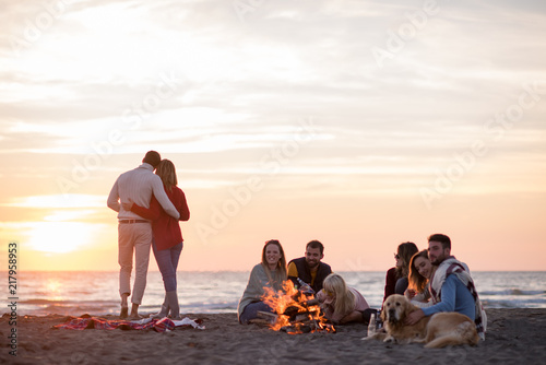 Couple enjoying with friends at sunset on the beach photo