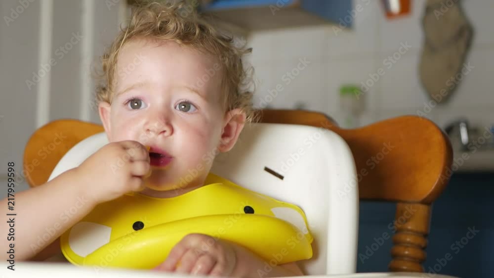 baby eating in high chair puts heritage tomato in mouth then uses sign language to ask for more