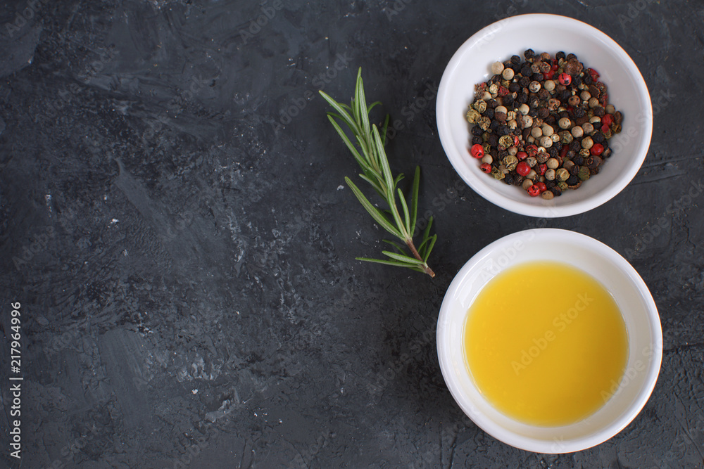 Olive oil porcelain plate Rosemary branch Pepper mix Cooking concept Seasoning Spices Black concrete background Top view Copy space Flat lay Olive oil porcelain plate Rosemary branch Pepper mix Cooking concept Seasoning Spices Black concrete background Top view Copy space Flat lay