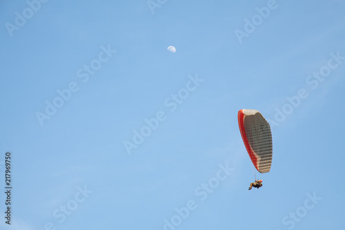 Paraglider flying with moon in the background