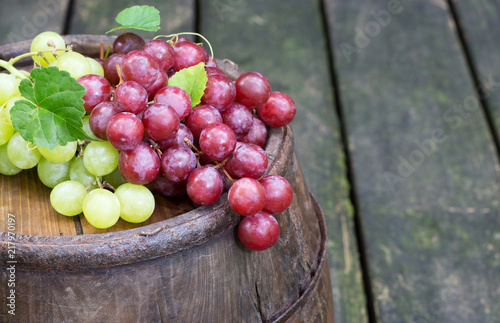 Red and Green Grapes on top of an Old Wine Barrel