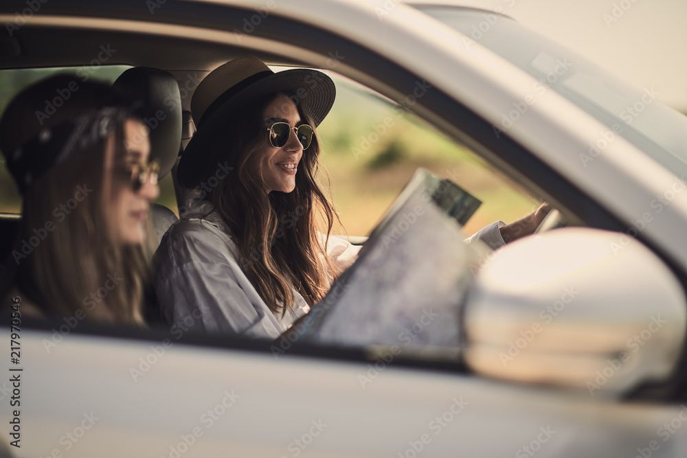 Two girls having fun driving. One girl driving and other reading the map.