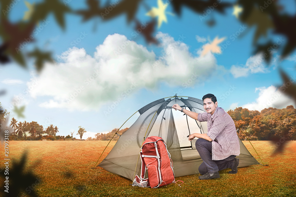 Young asian man set up a tent outdoors