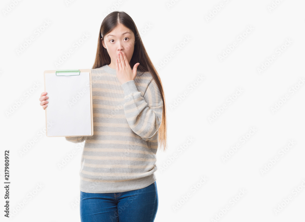 Young Chinese woman over isolated background holding clipboard cover mouth with hand shocked with shame for mistake, expression of fear, scared in silence, secret concept Young Chinese woman over isolated background holding clipboard cover mouth with hand shocked with shame for mistake, expression of fear, scared in silence, secret concept