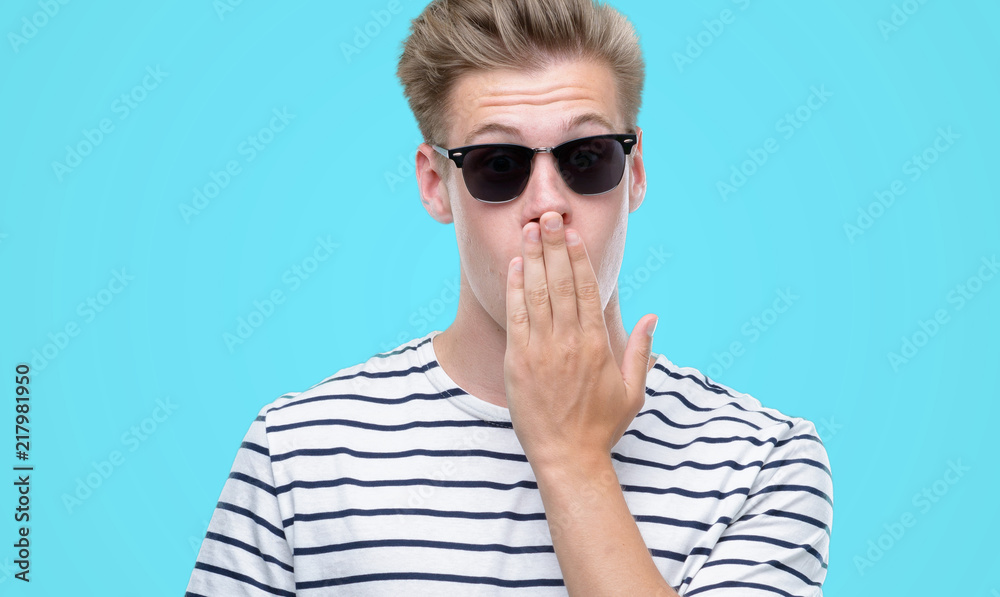 Fototapeta premium Young handsome blond man wearing sunglasess cover mouth with hand shocked with shame for mistake, expression of fear, scared in silence, secret concept