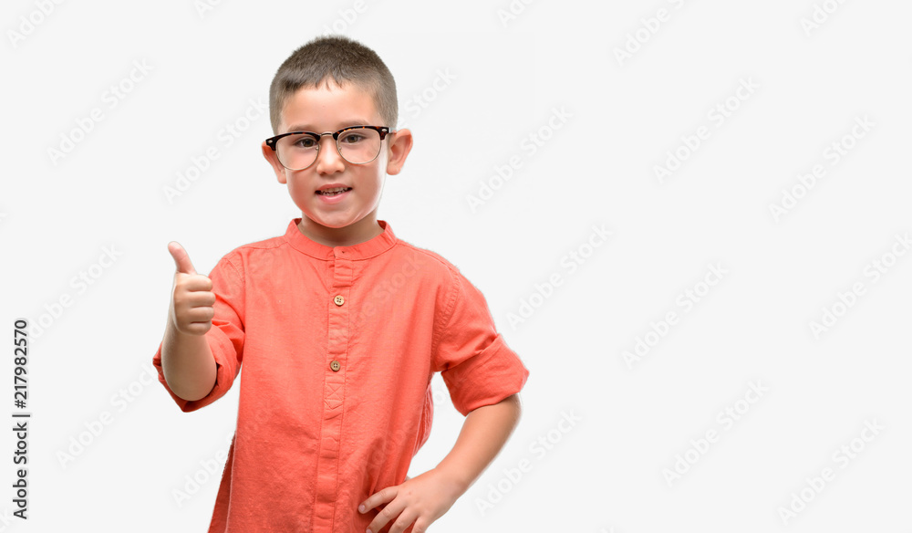 Dark haired little child wearing glasses happy with big smile doing ok sign, thumb up with fingers, excellent sign Dark haired little child wearing glasses happy with big smile doing ok sign, thumb up with fingers, excellent sign