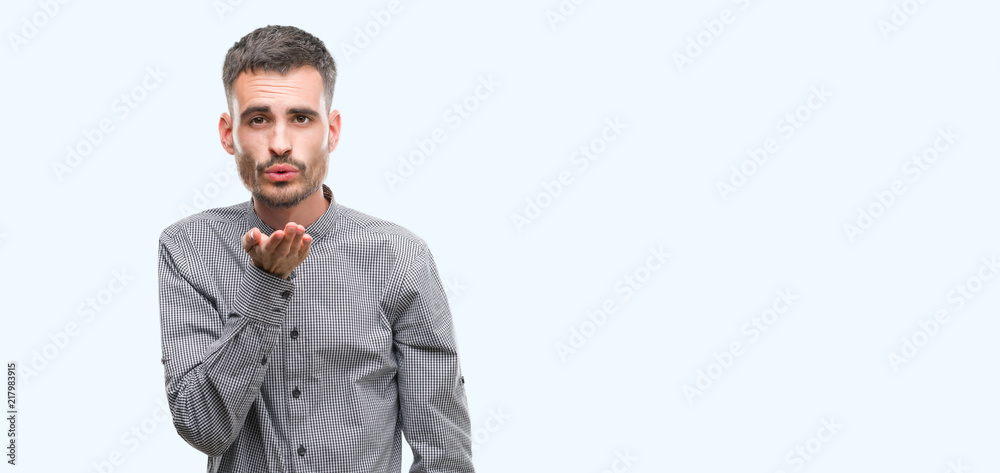 Young hipster man looking at the camera blowing a kiss with hand on air being lovely and sexy. Love expression. Young hipster man looking at the camera blowing a kiss with hand on air being lovely and sexy. Love expression.