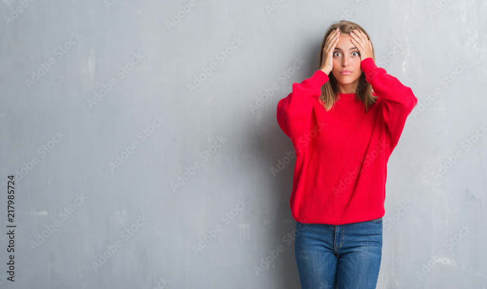 Beautiful young woman standing over grunge grey wall wearing winter sweater stressed with hand on head, shocked with shame and surprise face, angry and frustrated. Fear and upset for mistake. Beautiful young woman standing over grunge grey wall wearing winter sweater stressed with hand on head, shocked with shame and surprise face, angry and frustrated. Fear and upset for mistake.