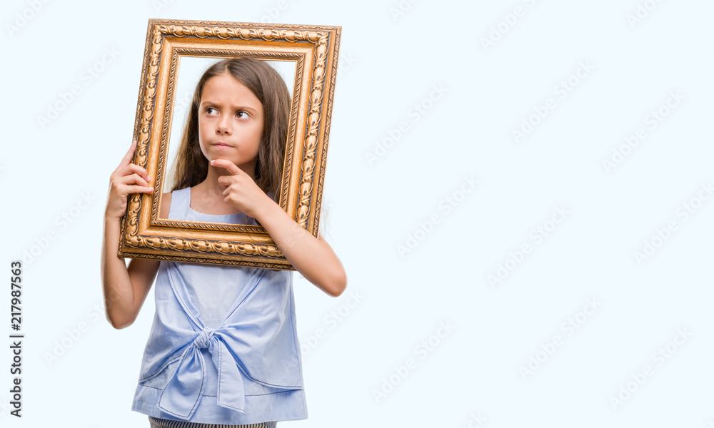 Fototapeta premium Brunette hispanic girl holding vintage art frame serious face thinking about question, very confused idea