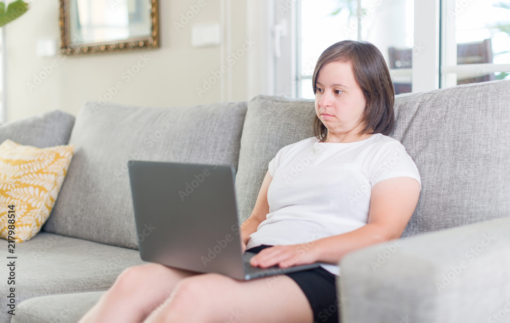 Down syndrome woman at home using computer laptop with a confident expression on smart face thinking serious Down syndrome woman at home using computer laptop with a confident expression on smart face thinking serious