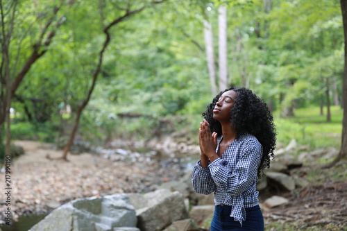 Pure black woman praying in nature