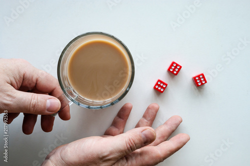 Hands rolling red dice six seals  a glass mug of coffee   isolated background  top view.