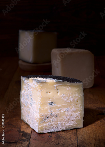 pieces of cheese in dark ambience on rustic wooden board