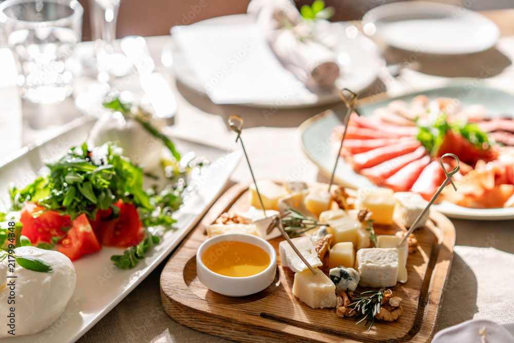 Cheese plate. Delicious cheese mix with walnuts, honey on wooden table. Tasting dish on a wooden plate. Food for wine. Cheese plate. Delicious cheese mix with walnuts, honey on wooden table. Tasting dish on a wooden plate. Food for wine.