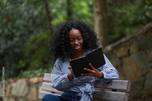 Content black woman enjoying reading on bench