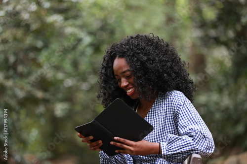 Young ethnic woman smiling while reading book