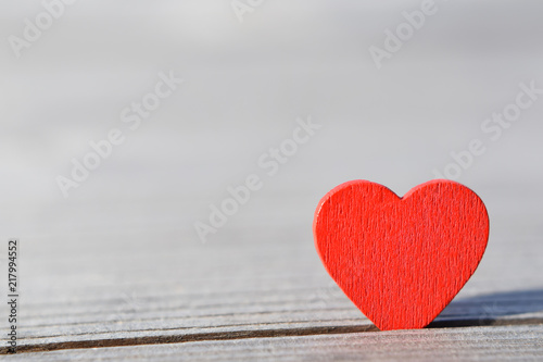 Red heart on light natural wood background with copy space for text. Love and valentines day card concept.