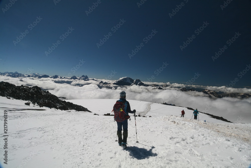 Tourist admires the Caucasus mountains from the slopes of mount Elbrus.