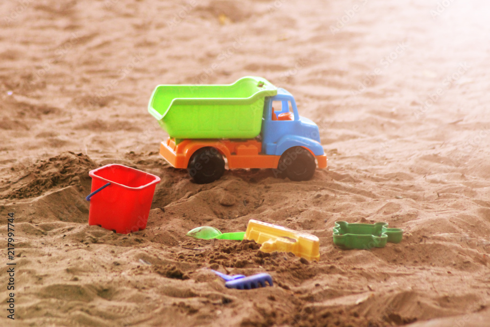 Children's beach toys - buckets, track and shovel on sand on a sunny day Children's beach toys - buckets, track and shovel on sand on a sunny day