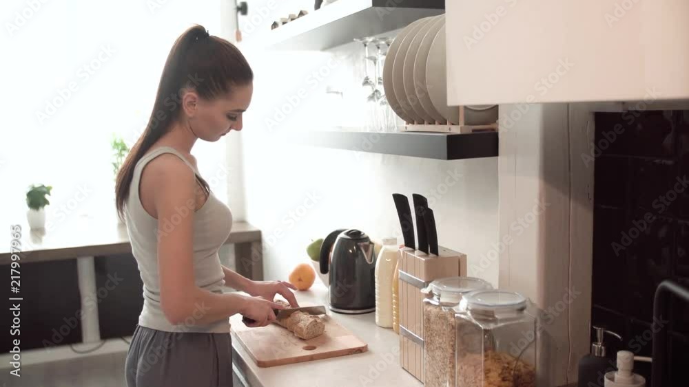 Woman Preparing Breakfast, Cutting Bread On Board In Kitchen Woman Preparing Breakfast, Cutting Bread On Board In Kitchen