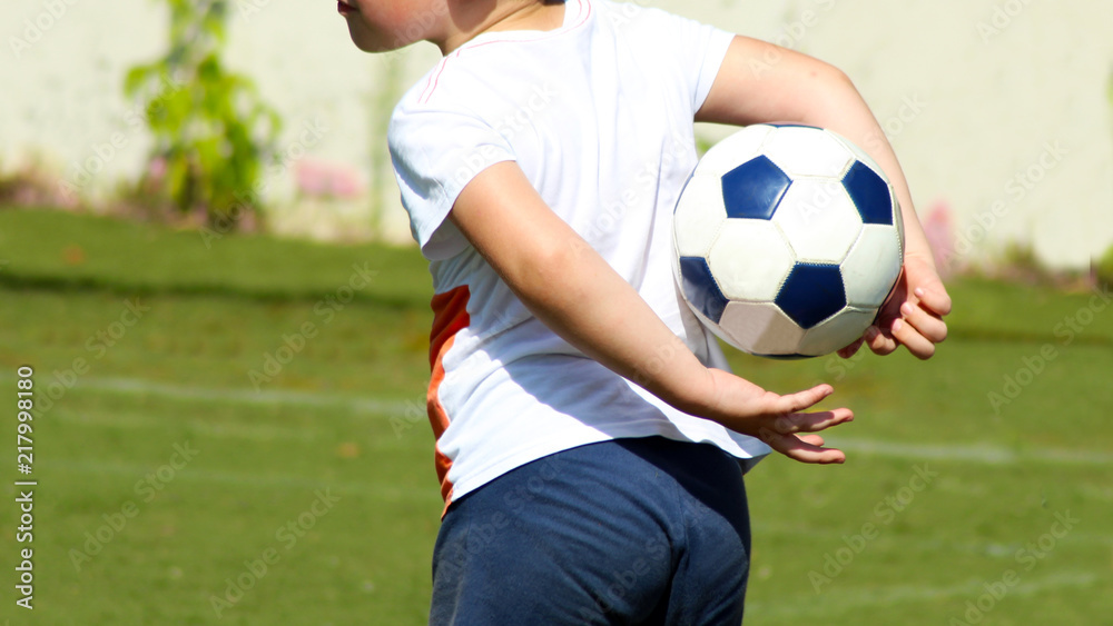 Obraz premium Boy holding a soccer ball behind his back