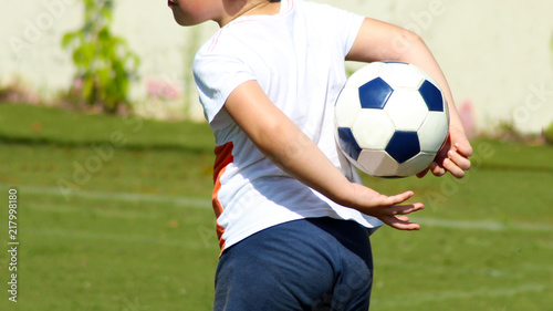 Boy holding a soccer ball behind his back