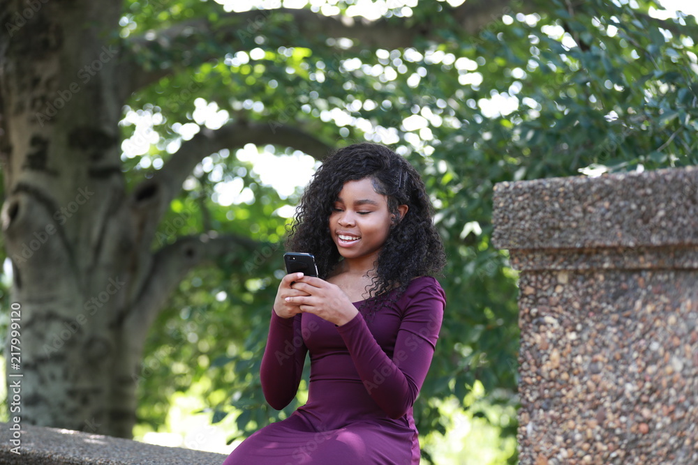 Smiling black female with smartphone in park Smiling black female with smartphone in park