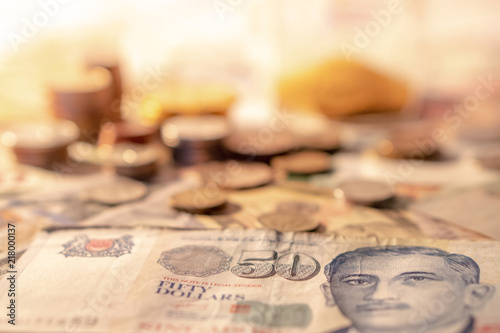 Photography Singapore dollar banknote with blurred gold coin stack in the background