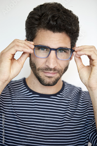 Dude adjusting glasses in studio, portrait