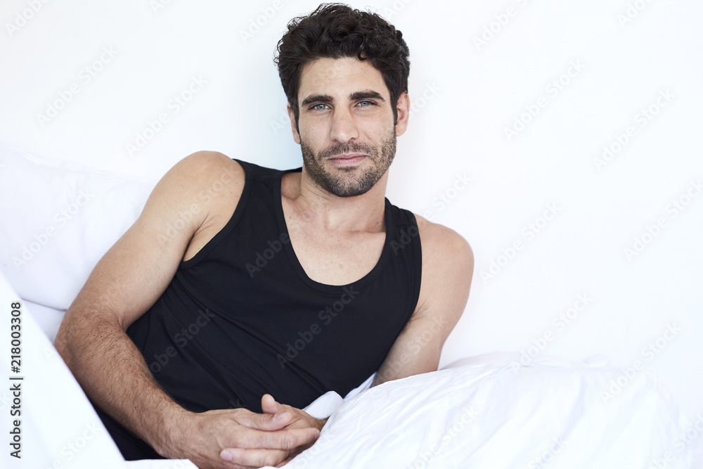 Good looking guy in bed, looking to camera