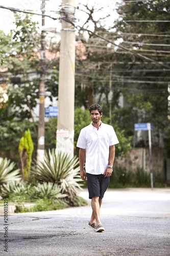 Shorts guy walking street, looking away