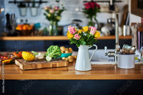 Wooden table with vegetables for cooking on defocused rustic kitchen background.
