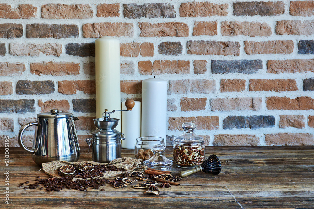 Composition of coffee beans, coffee mill, coffee pot and candles on the background of a brick wall. Dark rural still life.