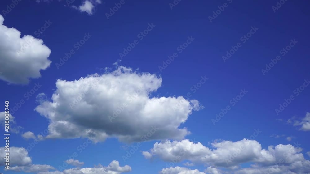 Beautiful bright blue cloudy sky background. White fluffy clouds slowly moving. Timelapse. Slow motion video footage.