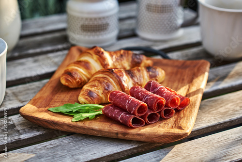 Slicing of Italian dry-cured ham prosciutto and croissants. Healthy eating concept.