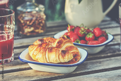Delicious breakfast with fresh croissants and ripe berries on old wooden background  selective focus.