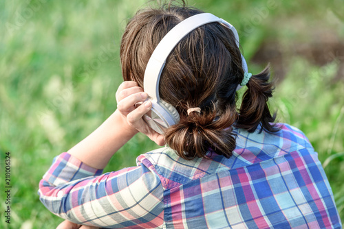 Girl listening to music with headphones in the grass