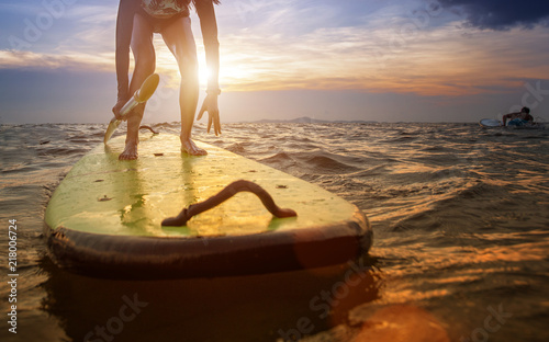 action of young woman try to step standing on the surfboard in the med of the sea, riding on the wave attemption skill training at beginer on surfboard photo