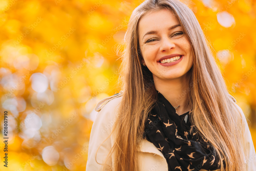 Cheerful young woman with sincere smile standing in a park in autumn. Cheerful young woman with sincere smile standing in a park in autumn.