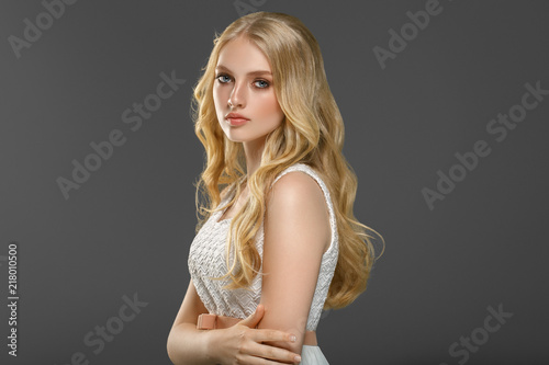 Stampa su tela Beautiful woman with long blonde hair over gray background beauty female